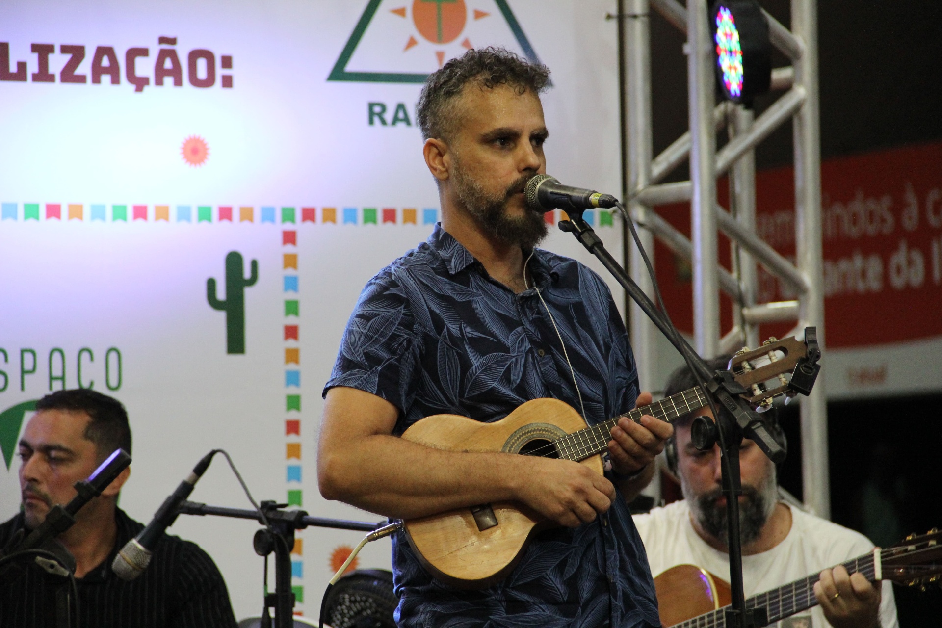 Músico cantando ao vivo no palco do Arraiá